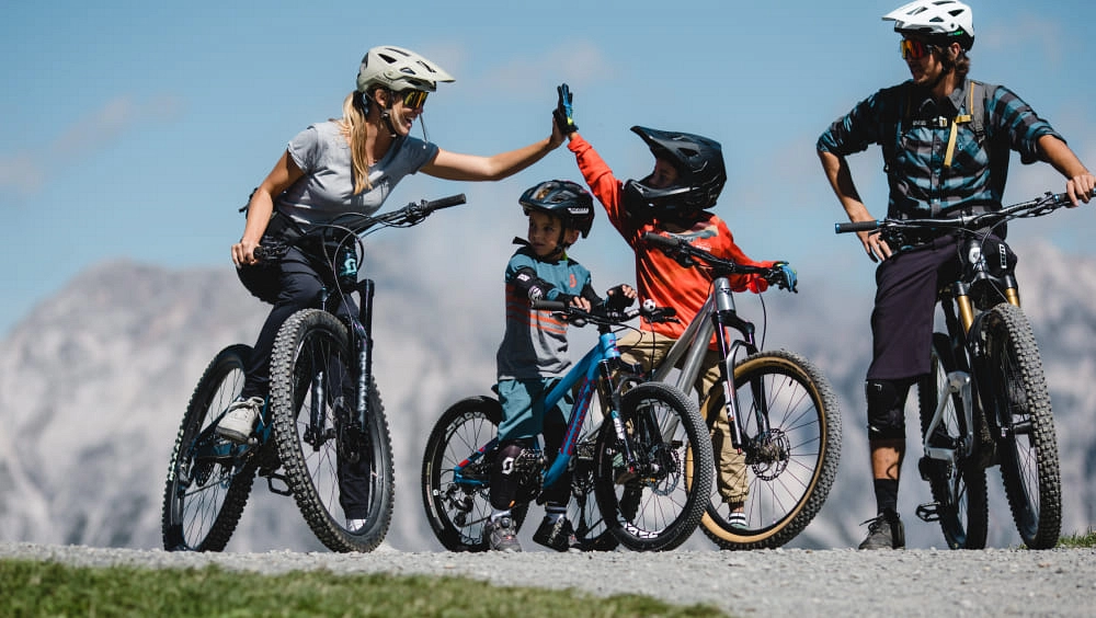 Familie beim Mountainbiken, hoch-fiving auf einem Weg in den Bergen.